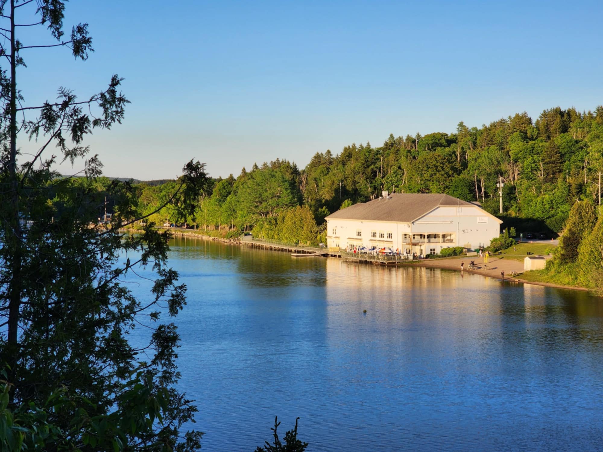 Scenic View of Lily Lake Pavilion at Rockwood Park: A picturesque view of Lily Lake Pavilion nestled along the shoreline of Lily Lake in Rockwood Park, surrounded by lush greenery and reflecting the serene water under a clear blue sky.